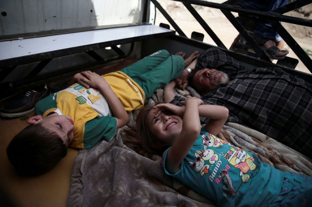 <em>“Two children play on the back of a truck while a man takes a nap, during a break in filming in the suburbs of Damascus, Syria, on September 19.”</em>