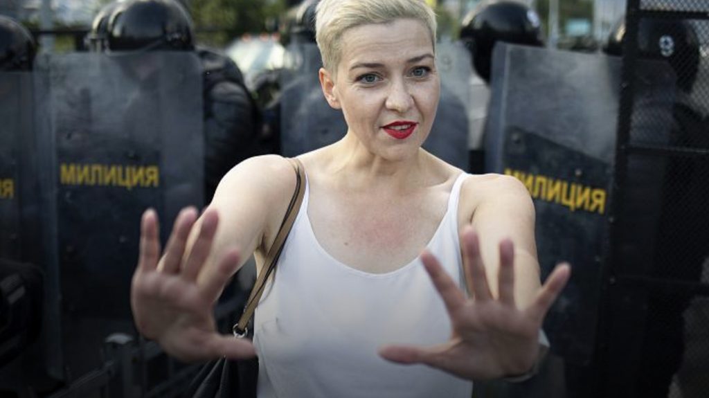 Maria Kolesnikova stands between Police and demonstrators, trying to prevent violence.