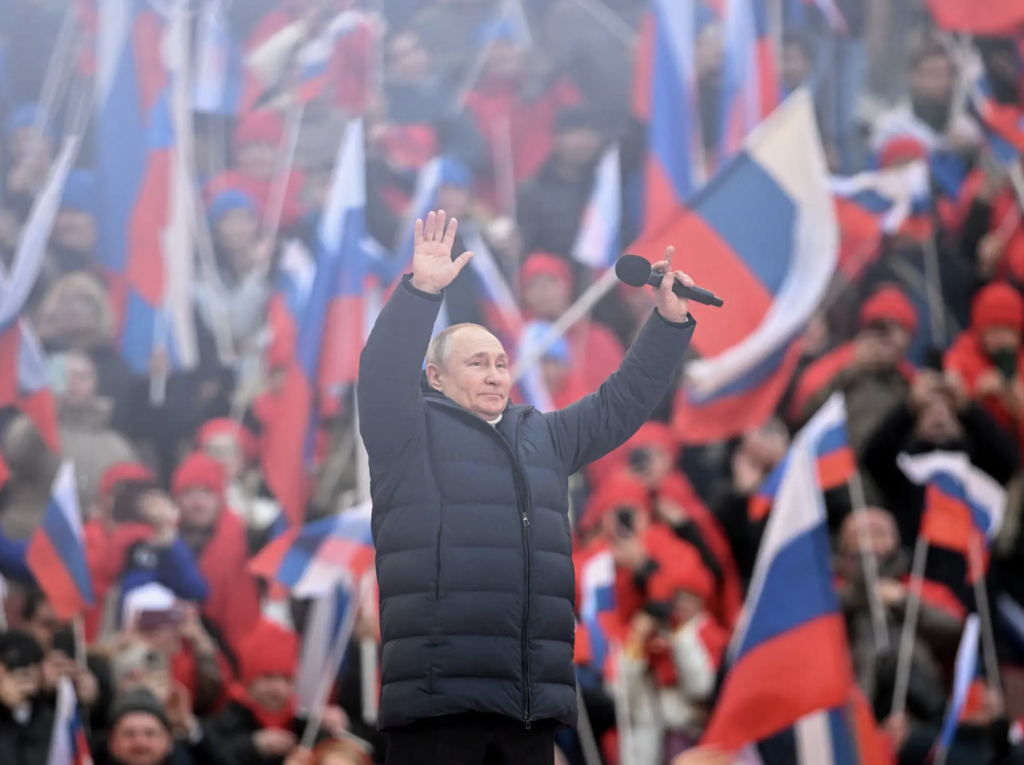 Vladimir Putin waving during a concert marking the eighth anniversary of Russia's annexation of Crimea at Luzhniki Stadium in Moscow
